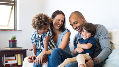 young family smiling and sat on sofa at home