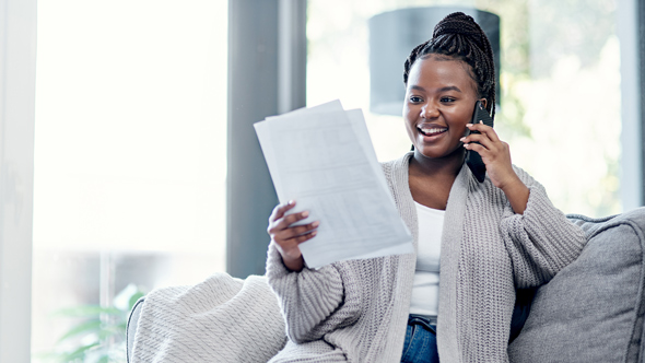 smiling woman on phone looking at papers in hand