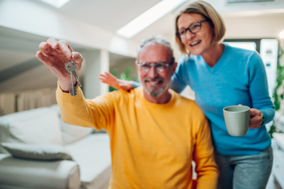 older couple smiling holding keys to house close up