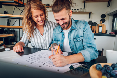 couple smiling and drawing plans for build of house