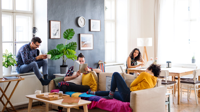 house share concept, multiple occupants relaxing on sofa chatting