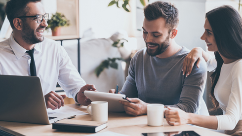 couple laughing and signing contract with financial adviser, drinking coffees