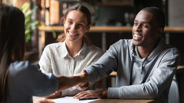 couple shaking hand with adviser over closed deal