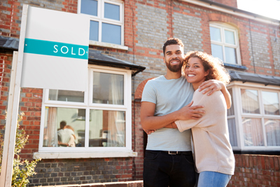 couple standing outside house with sold sign