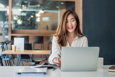 asian businesswoman sitting working on laptop in office